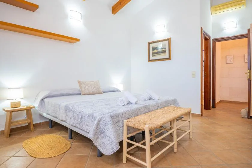 A bedroom with a bed, a wooden bench, and an open doorway.