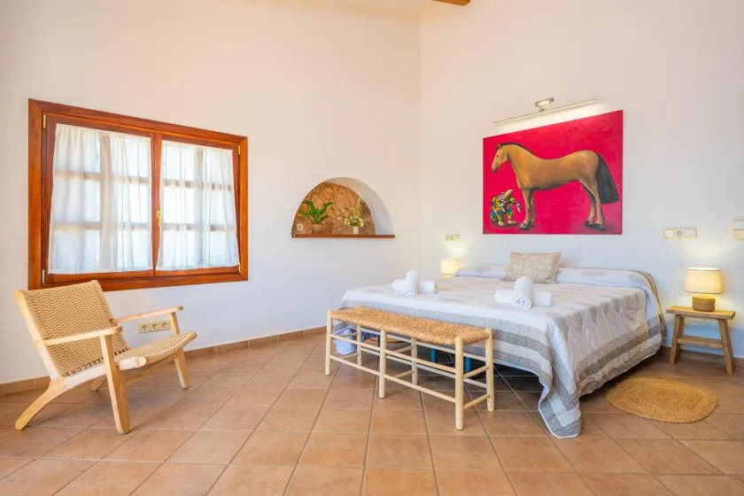 A bedroom with a bed, a window, and a woven chair.