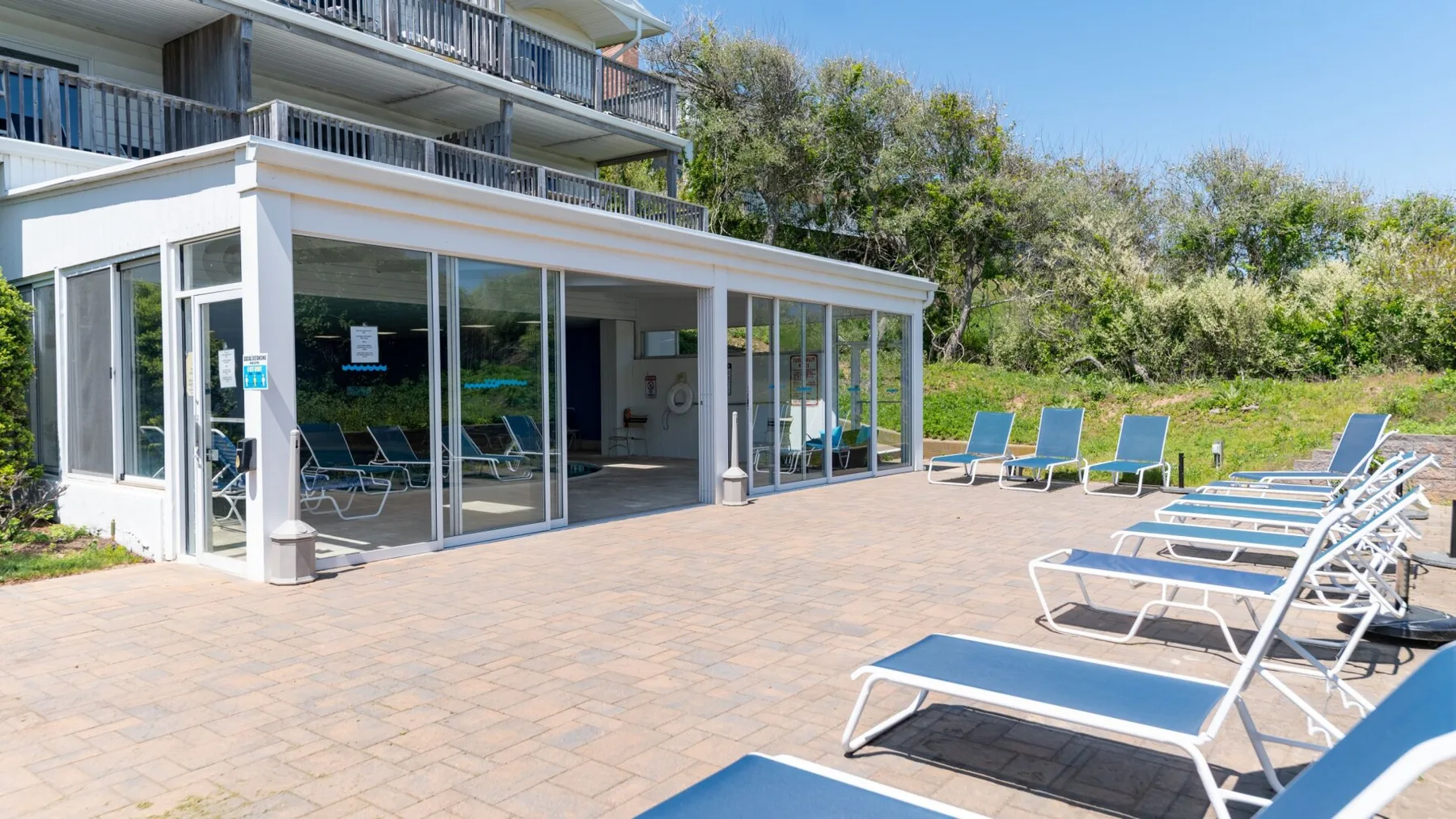 A glass-fronted patio opens onto an outdoor seating area with lounge chairs.