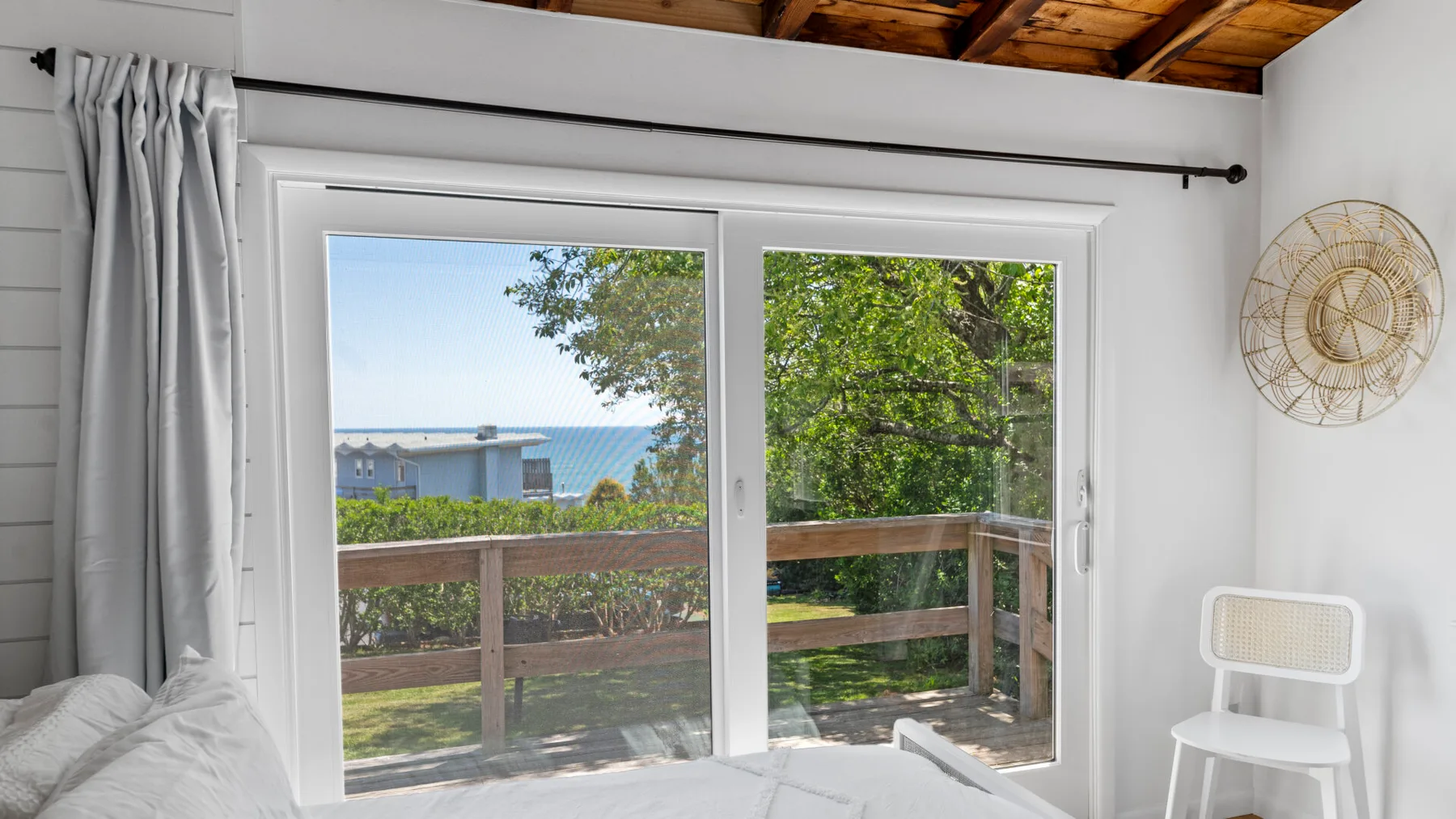 A bright room opens onto a wooden deck through large sliding glass doors.