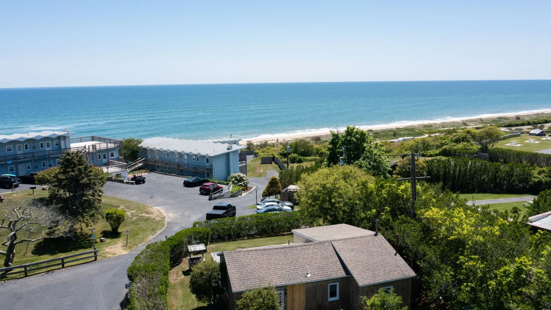A coastal scene with buildings, greenery, and the ocean in the background.