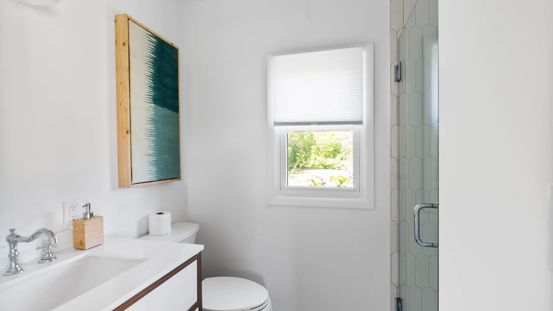 A bright bathroom with a sink, toilet, and glass shower.