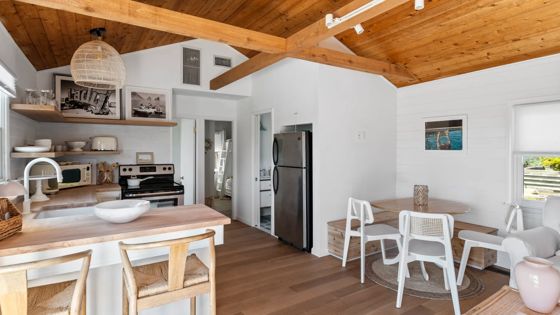 A bright open-plan kitchen and dining area with a wooden ceiling.