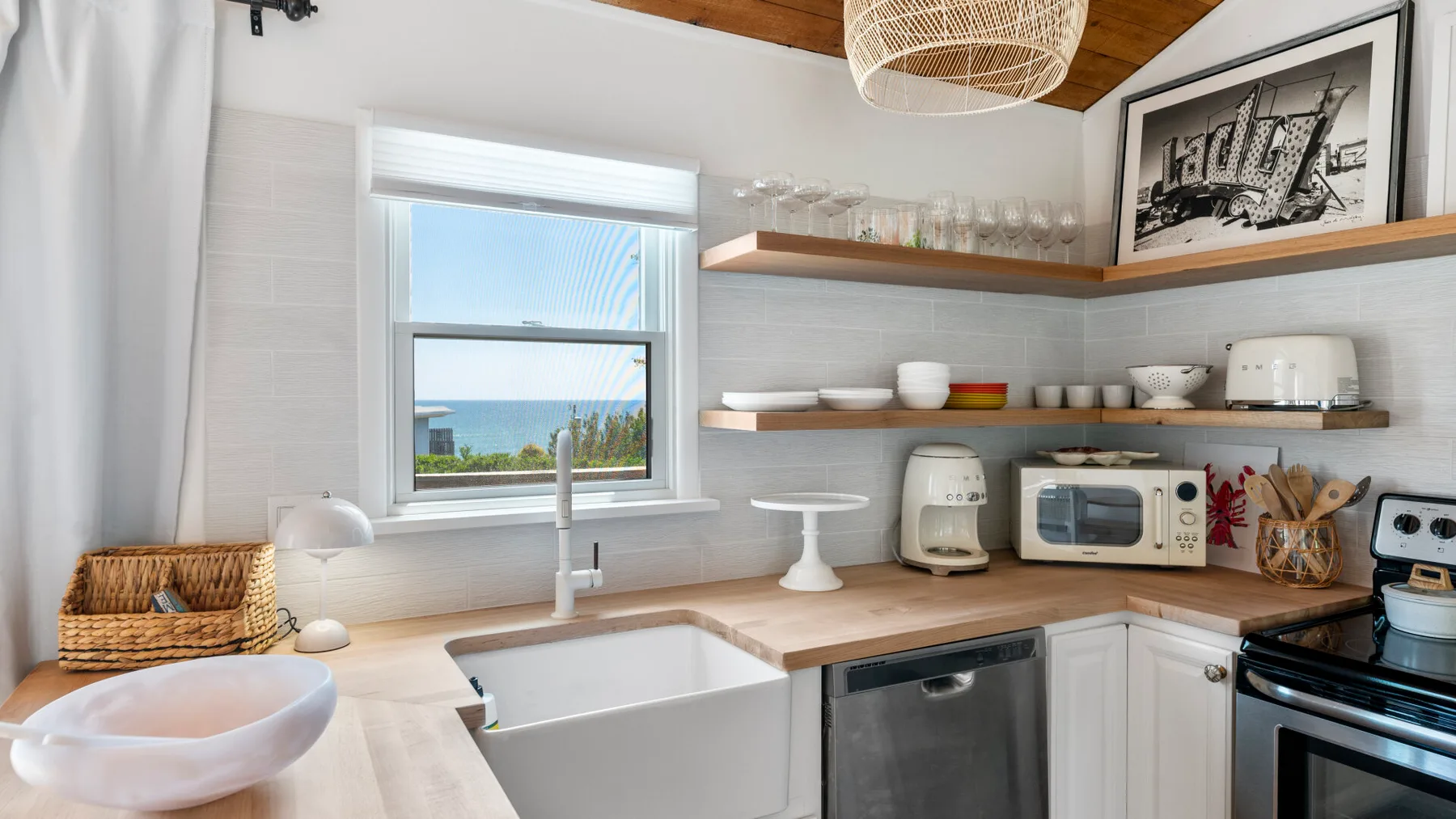 A bright kitchen with white cabinetry, a large sink, and a window overlooking greenery.