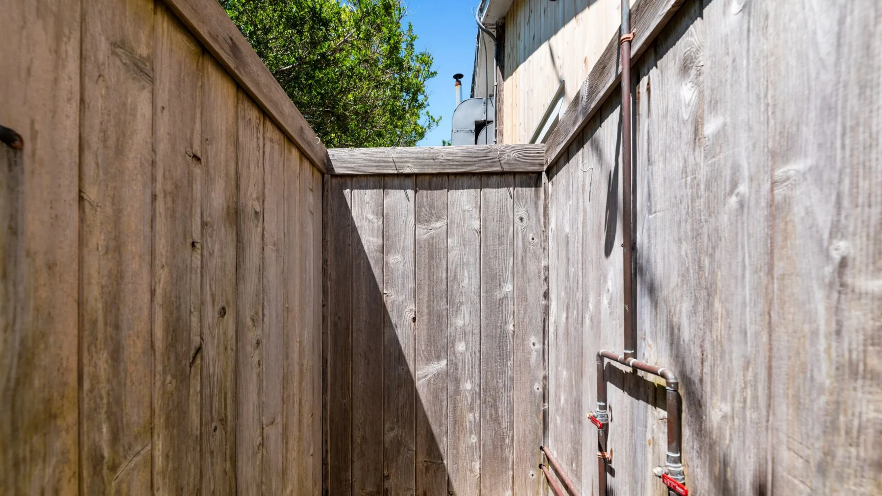 An outdoor shower area enclosed by wooden fencing, with a visible shower fixture.