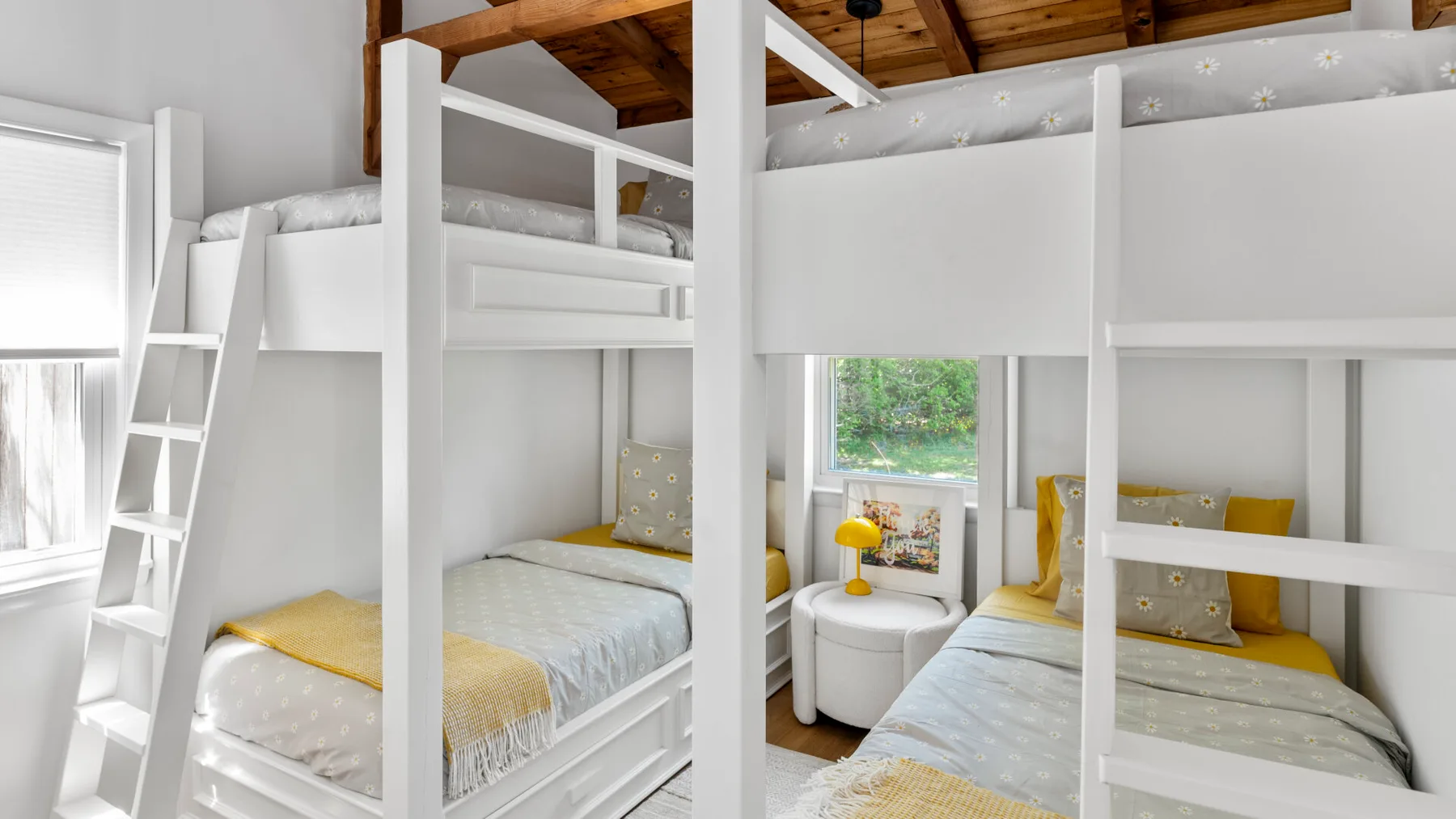 A bright bedroom with white bunk beds and a large window.
