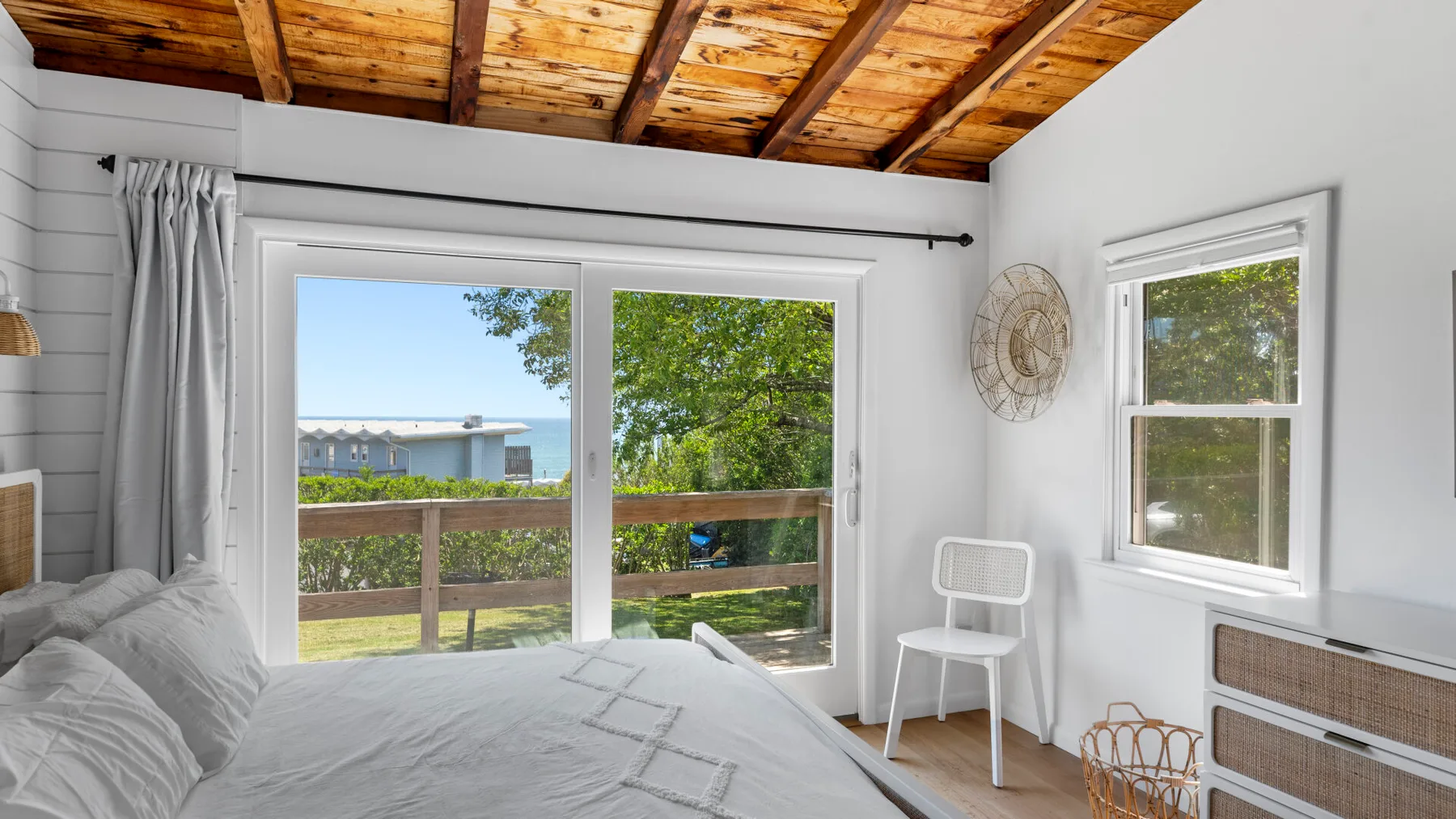 A bright bedroom opens onto a balcony through large glass doors.