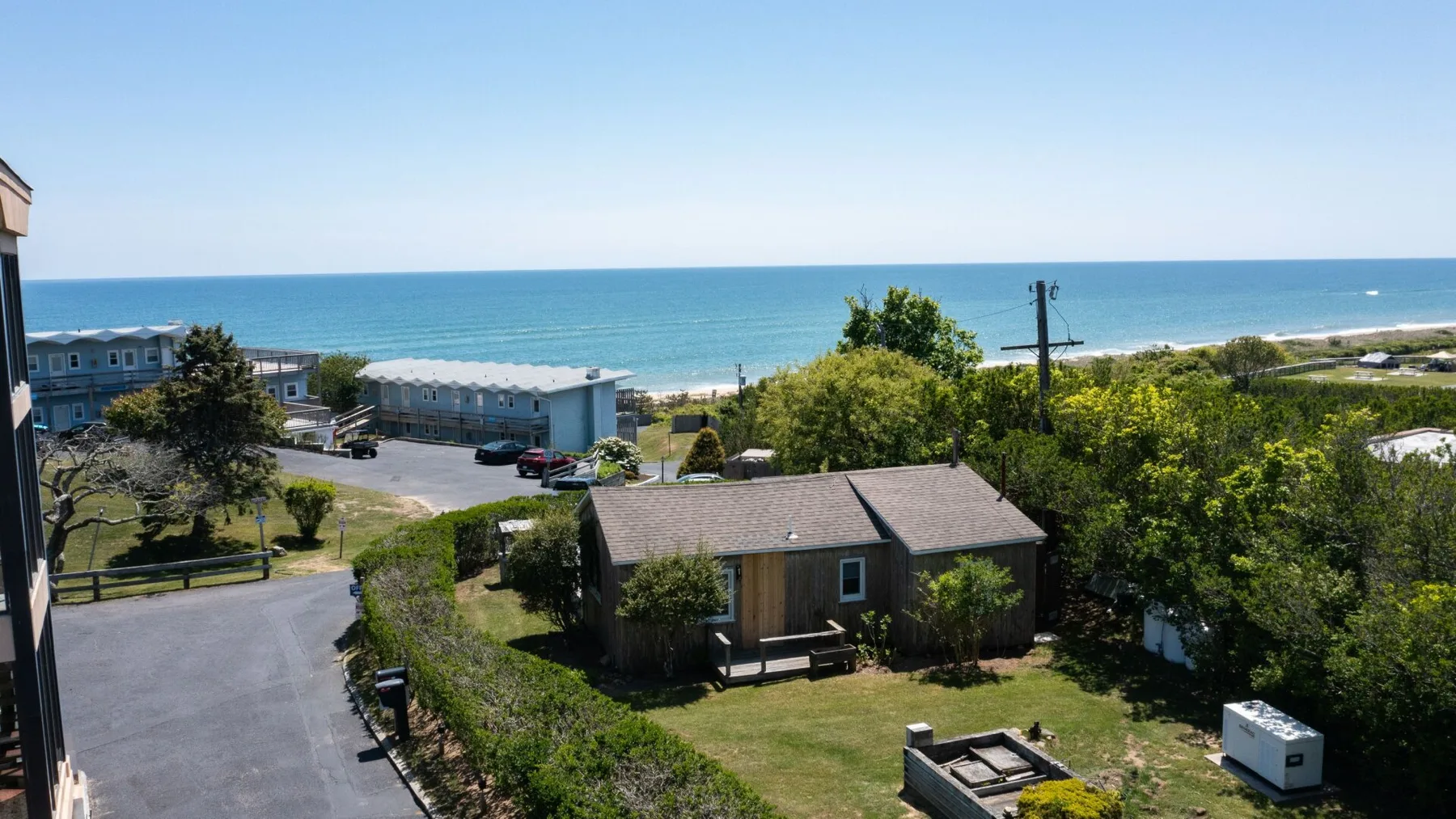 A small house sits among greenery with the ocean visible in the background.