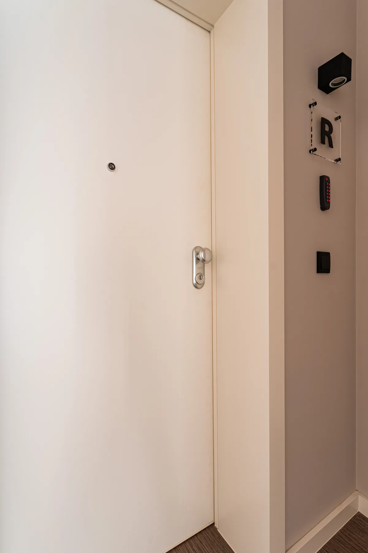 A white entry door with a peephole and metal handle.
