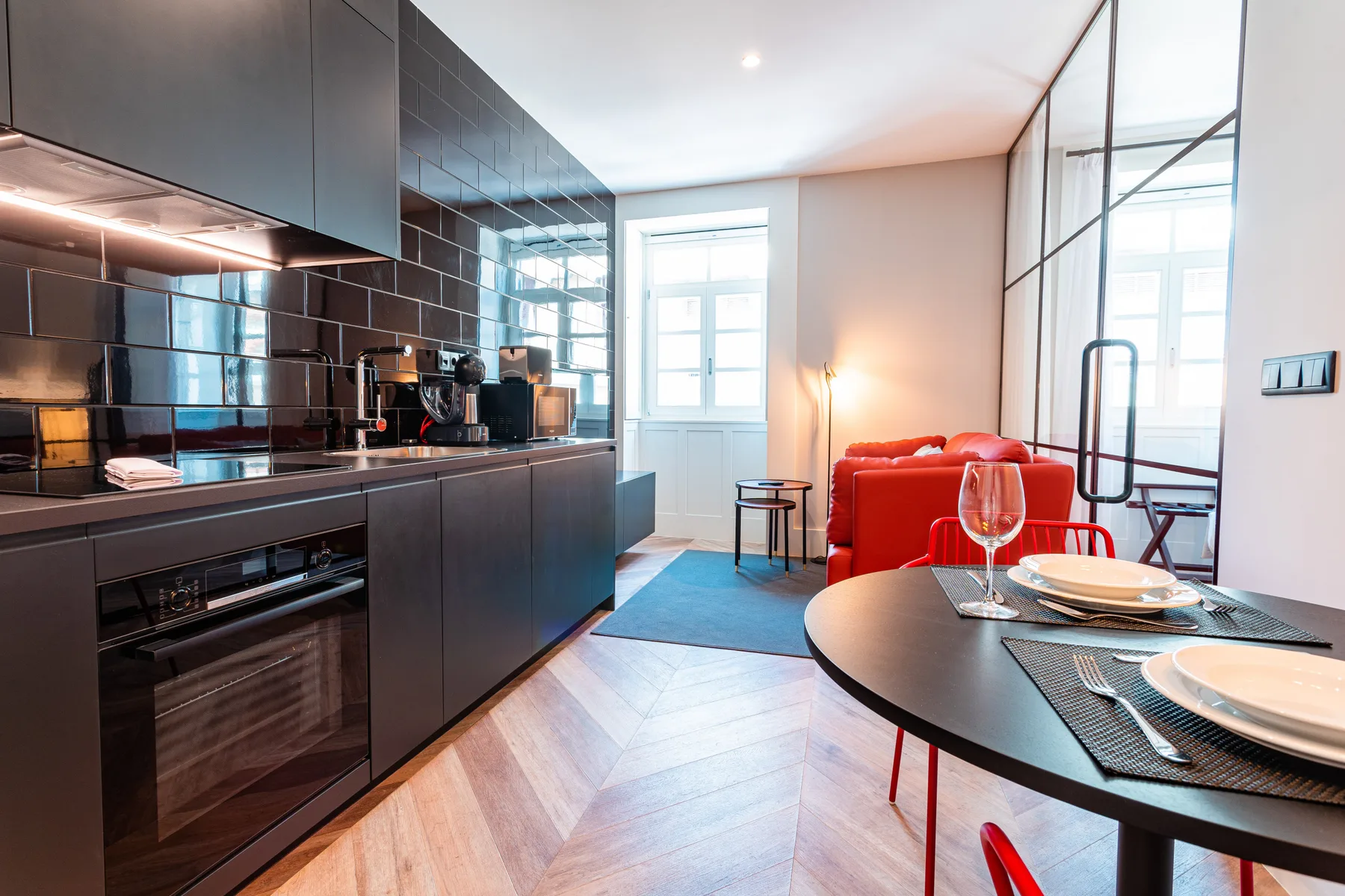 Una cocina moderna y zona de comedor con armarios oscuros y una mesa preparada para comer.