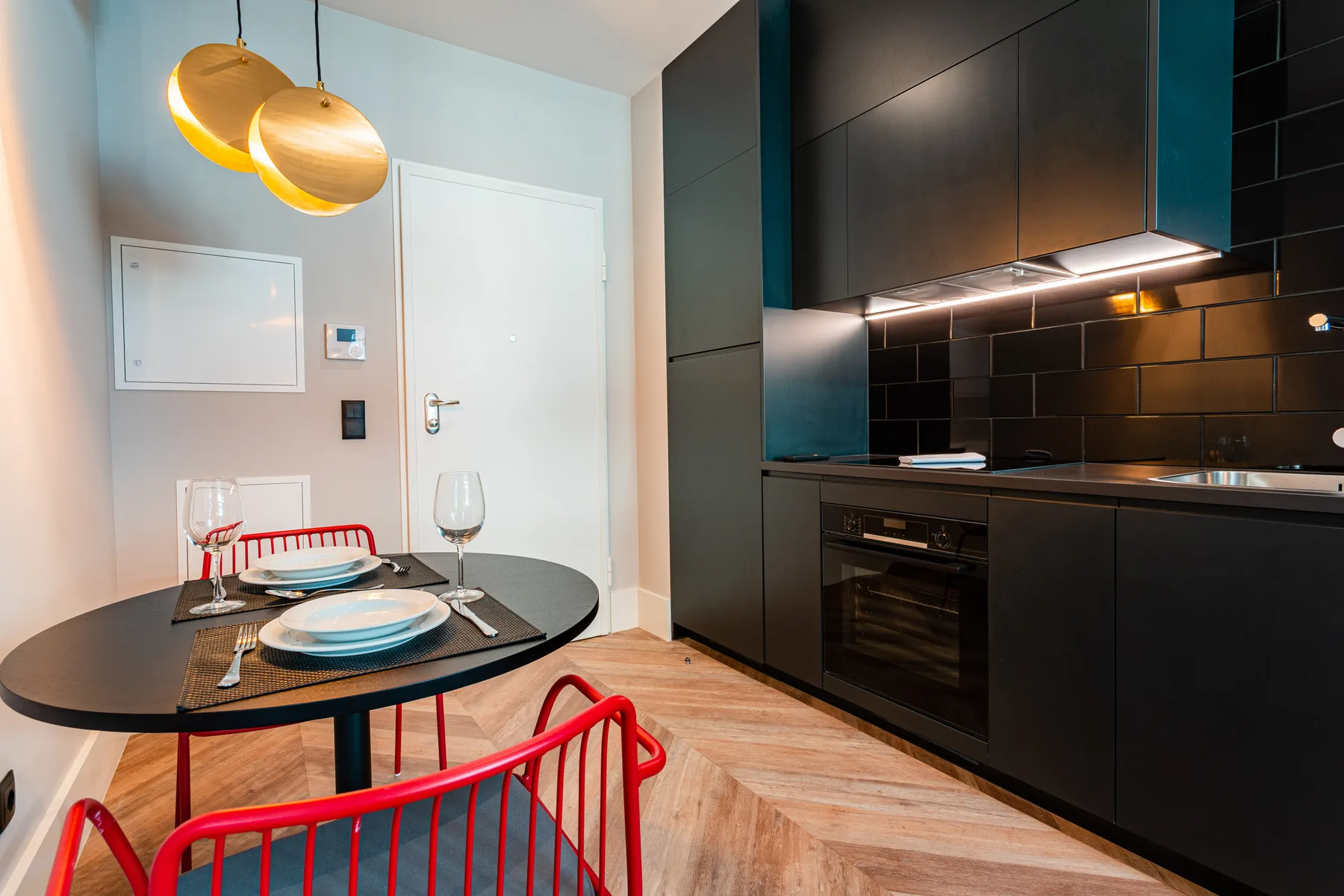 Una cocina y comedor compactos con armarios oscuros y una mesa pequeña.