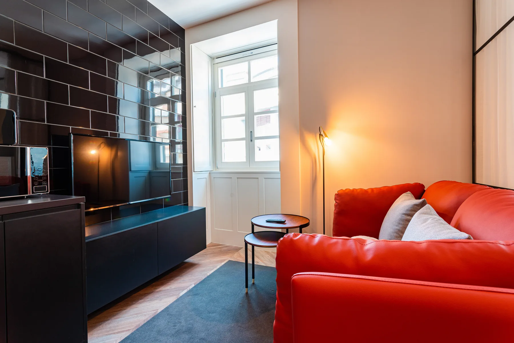 Una sala de estar con asientos rojos, una mesa de centro y una ventana grande.
