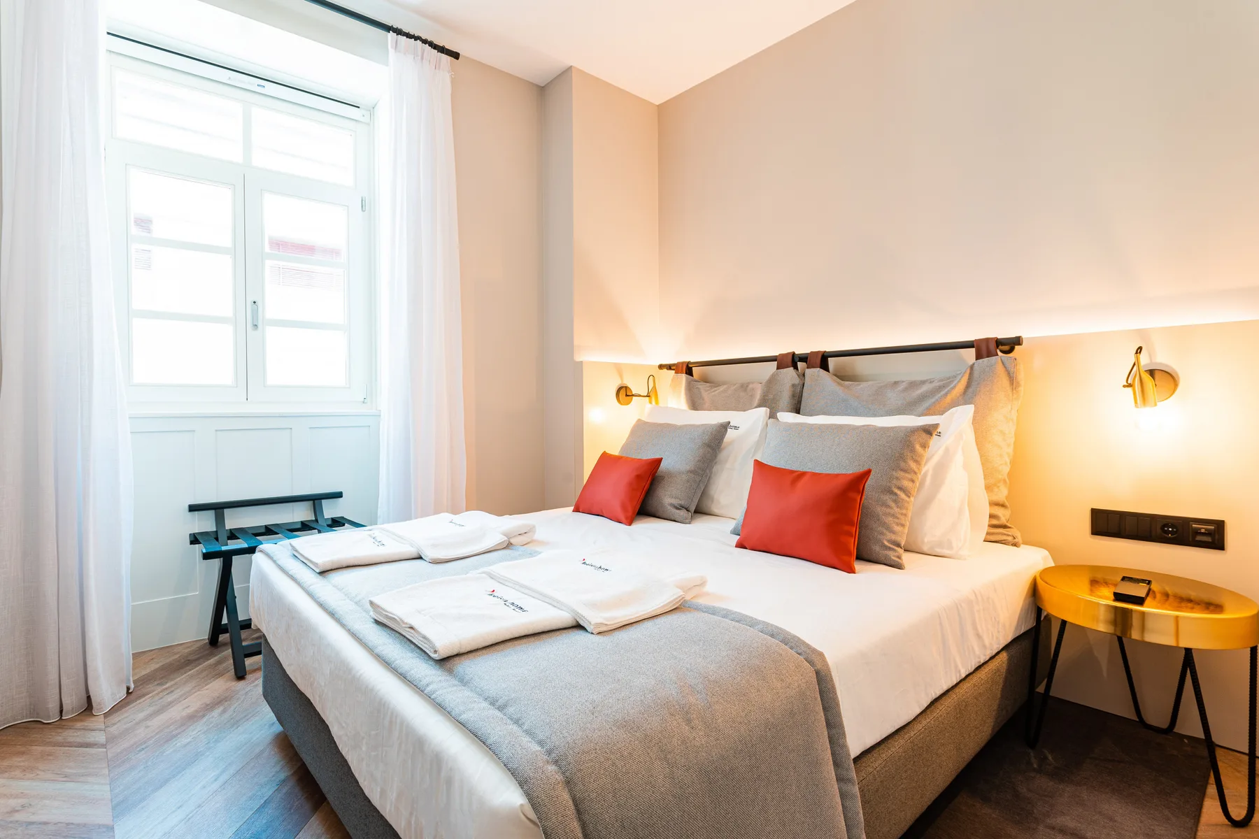 Un dormitorio con una cama bien hecha, cojines de colores y una ventana grande.