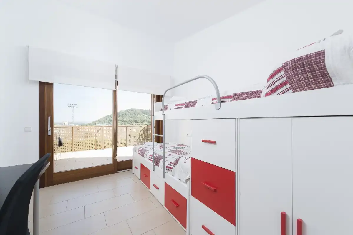 A bright bedroom with built-in beds and a glass door opening onto a balcony.