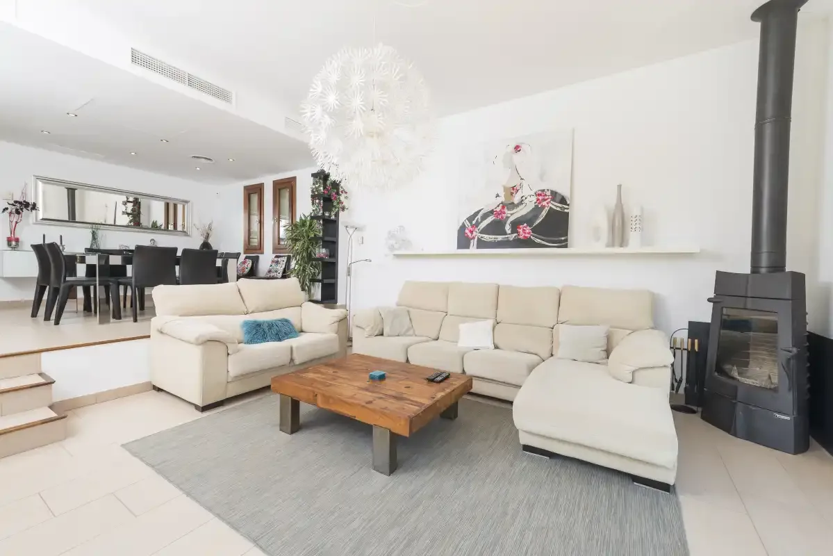 A bright living room with seating, a wooden coffee table, and a black freestanding stove.