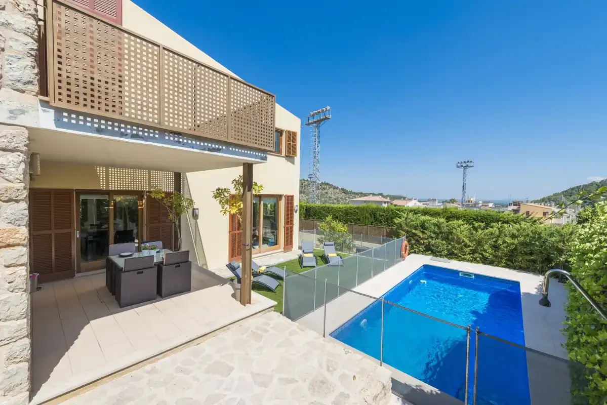 A modern house patio overlooks a swimming pool and garden.