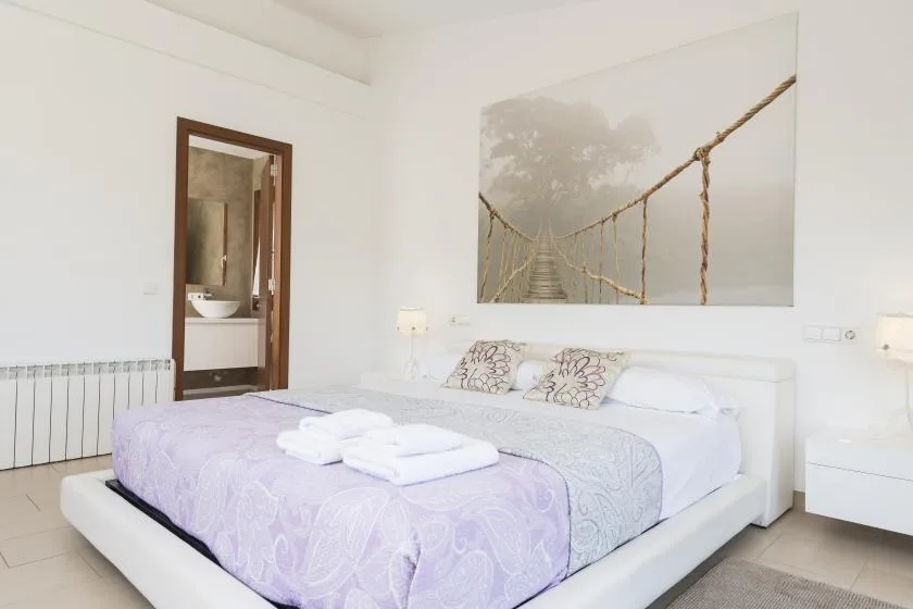 A bright bedroom with a neatly made bed and a large bridge photograph above it.