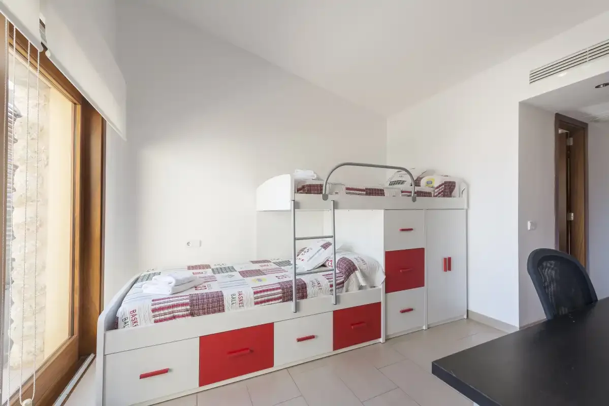 A bright bedroom with a built-in bunk bed beside a large window.