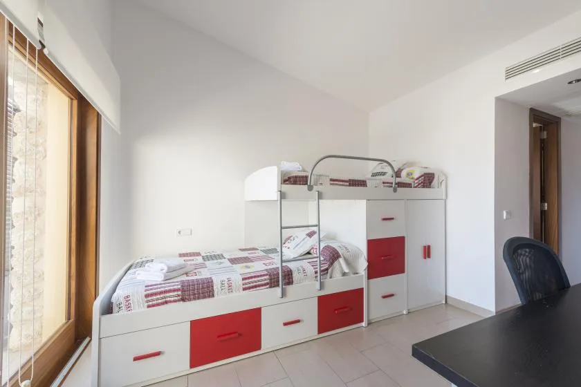 A bright bedroom features bunk beds with built-in storage.