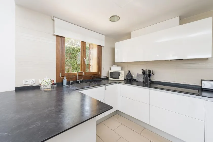 A bright kitchen with white cabinets and a dark countertop.