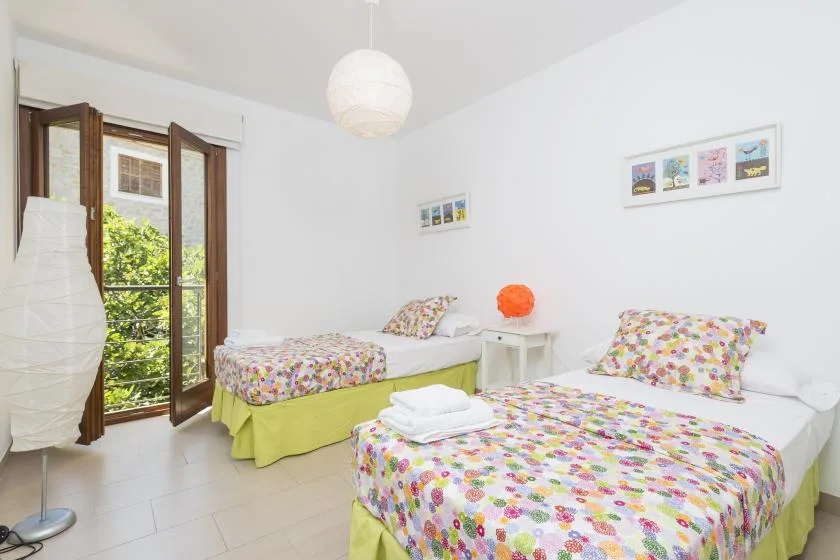 A bright bedroom with two beds covered in colorful floral bedding.