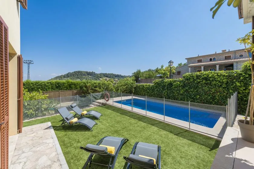 A poolside patio with loungers overlooks a long outdoor swimming pool.