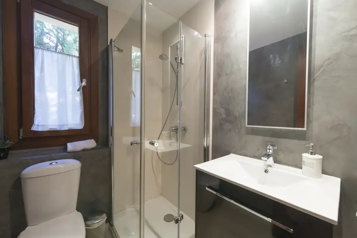 A bathroom with a glass shower and a wide white sink.
