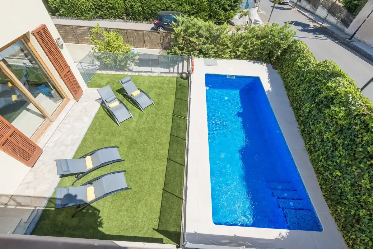 An outdoor swimming pool beside a lawn with lounge seating.