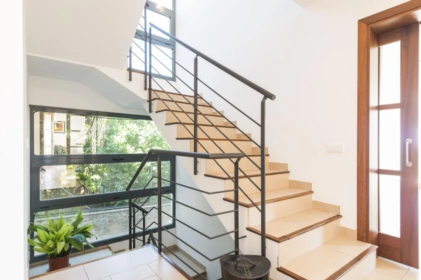 A bright interior stairway with dark railings and large windows.