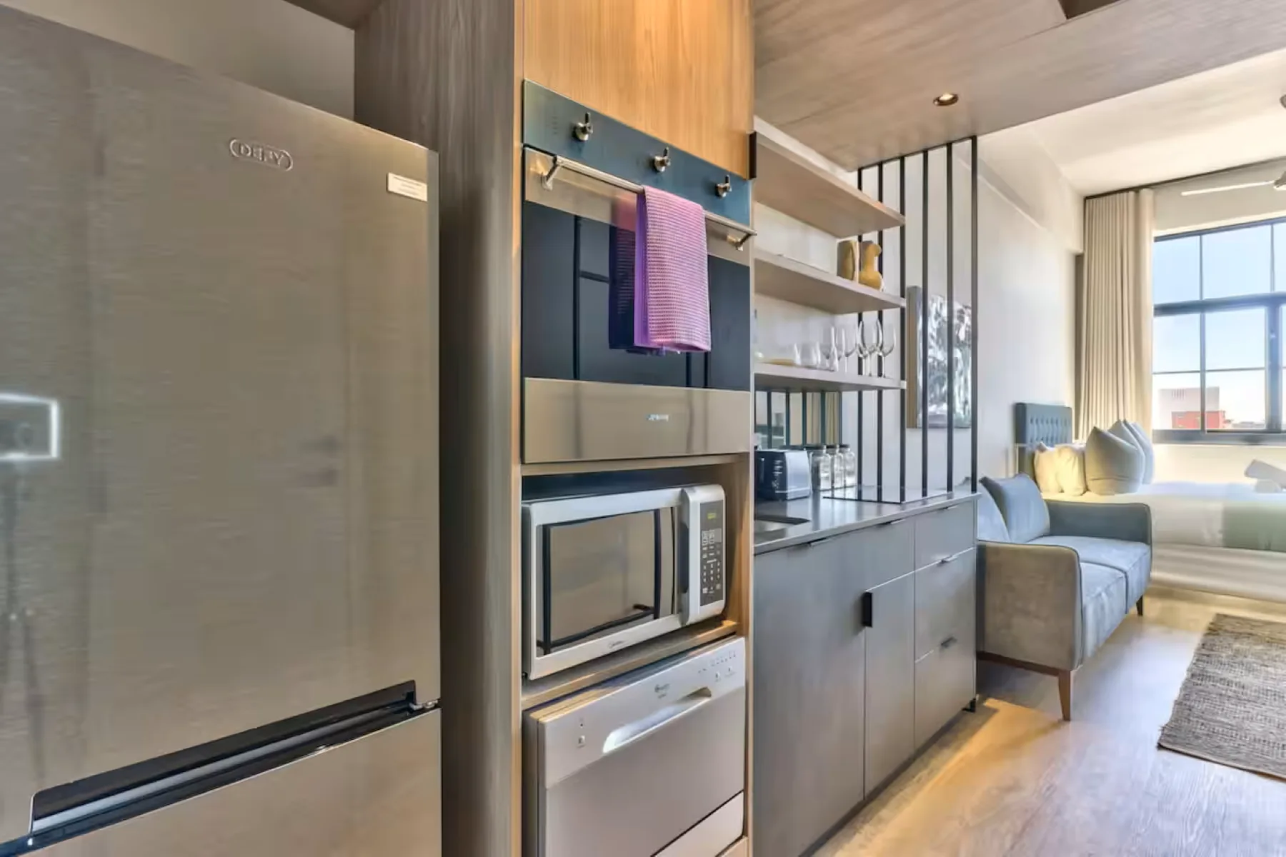 A modern kitchen with built-in appliances opens onto a bright seating area.