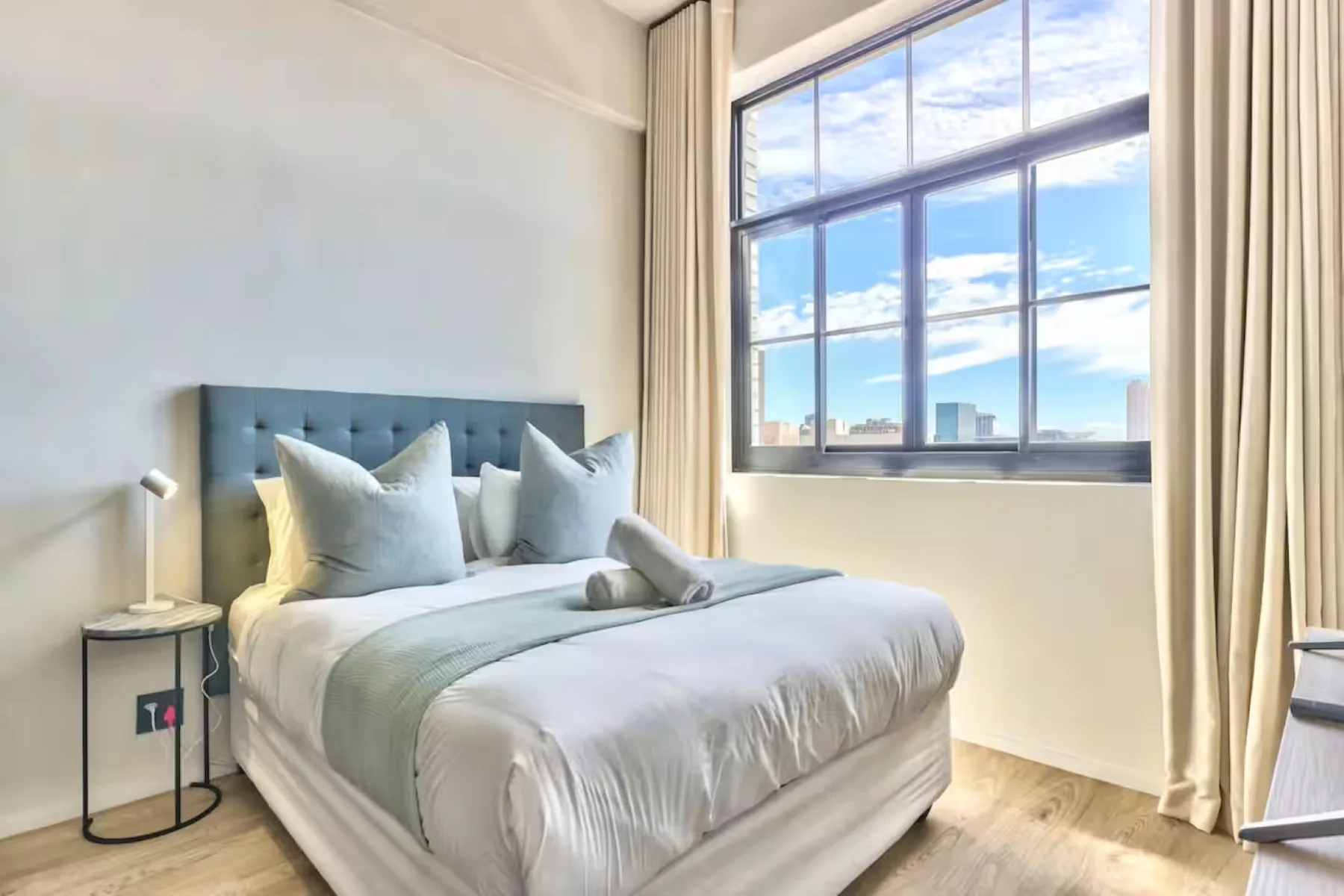 A bedroom with a neatly made bed beside a large window.