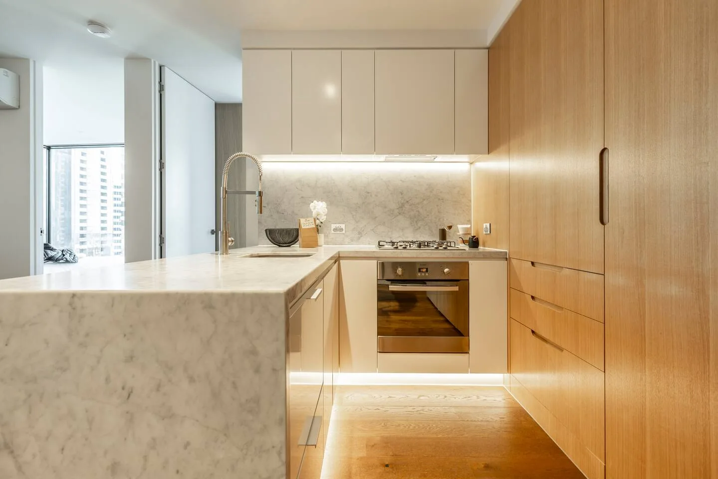 A modern kitchen with light cabinetry, a countertop, and a built-in oven.