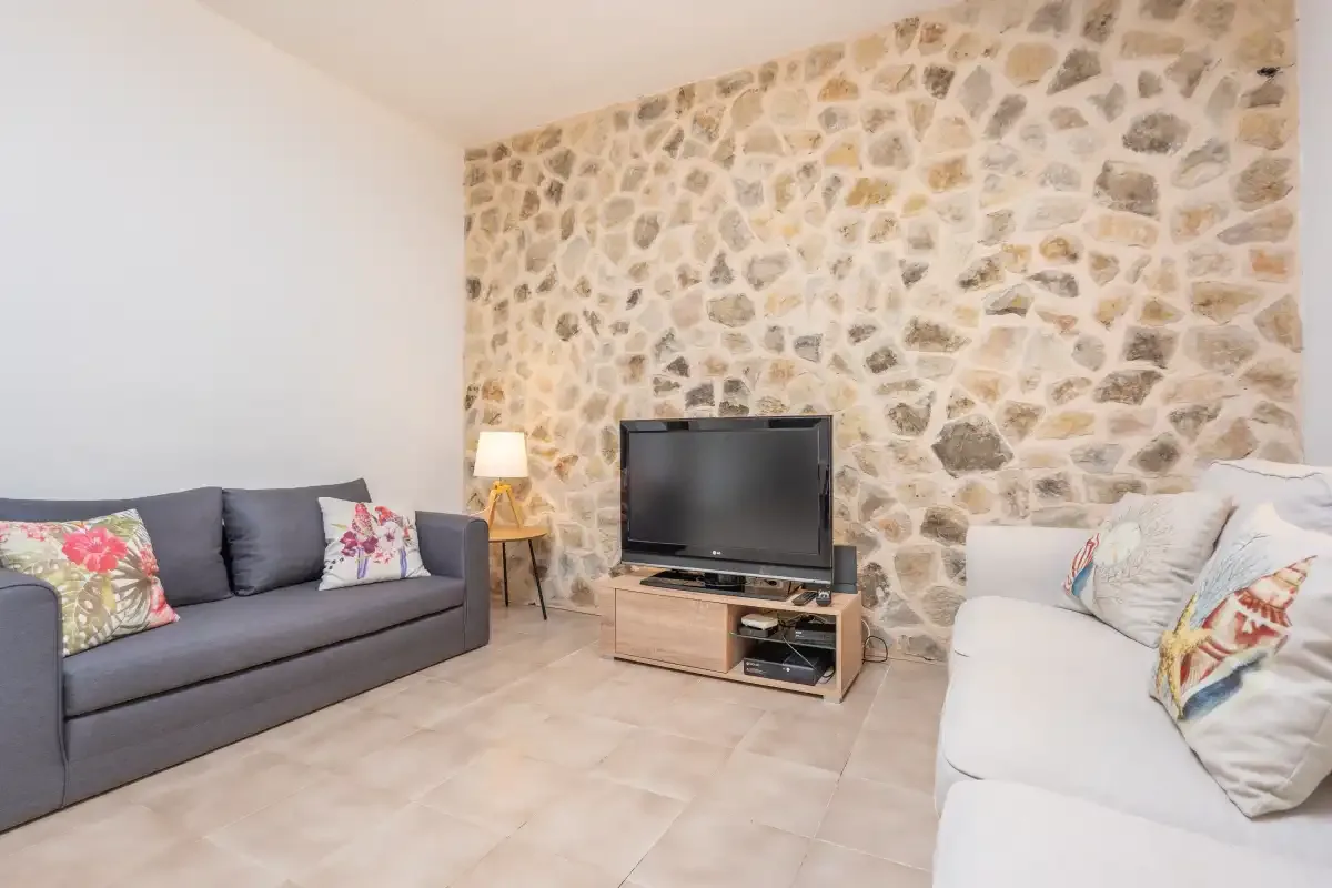Una sala de estar con asientos, un televisor y una pared de piedra.