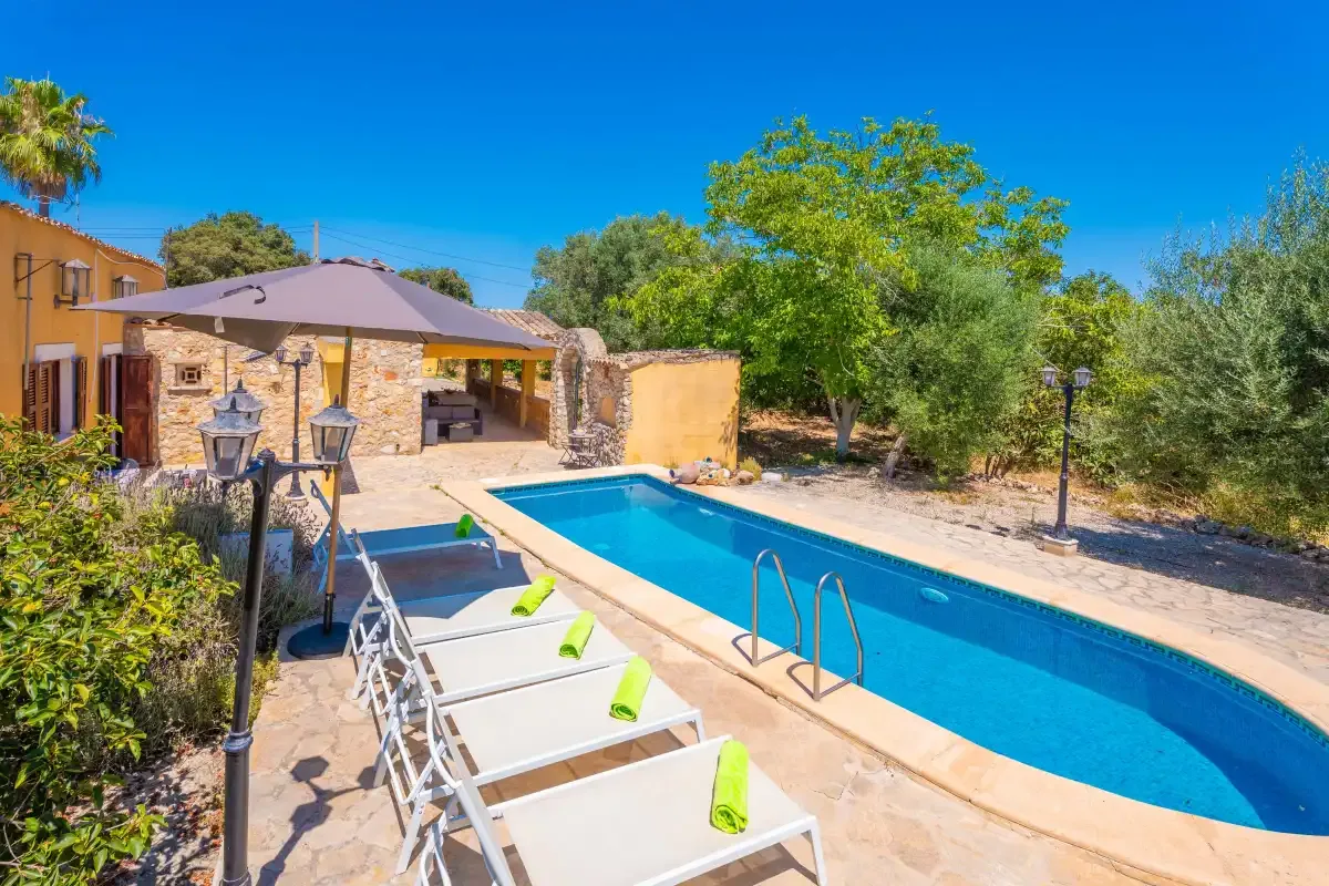 Una piscina al aire libre junto a un patio de piedra y un jardín.