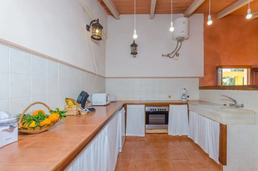 Una cocina con encimeras de azulejos, armarios blancos y un horno pequeño.