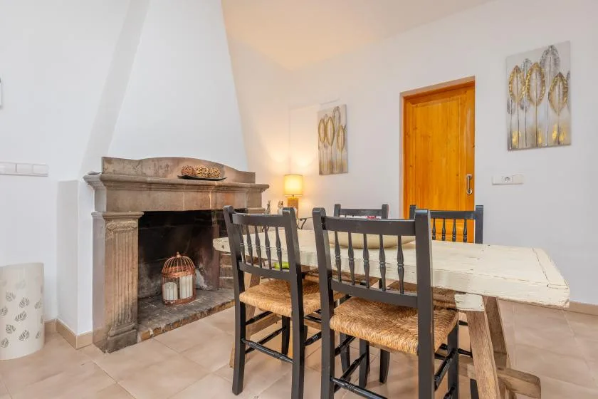 Comedor con una mesa y sillas junto a una chimenea de piedra.