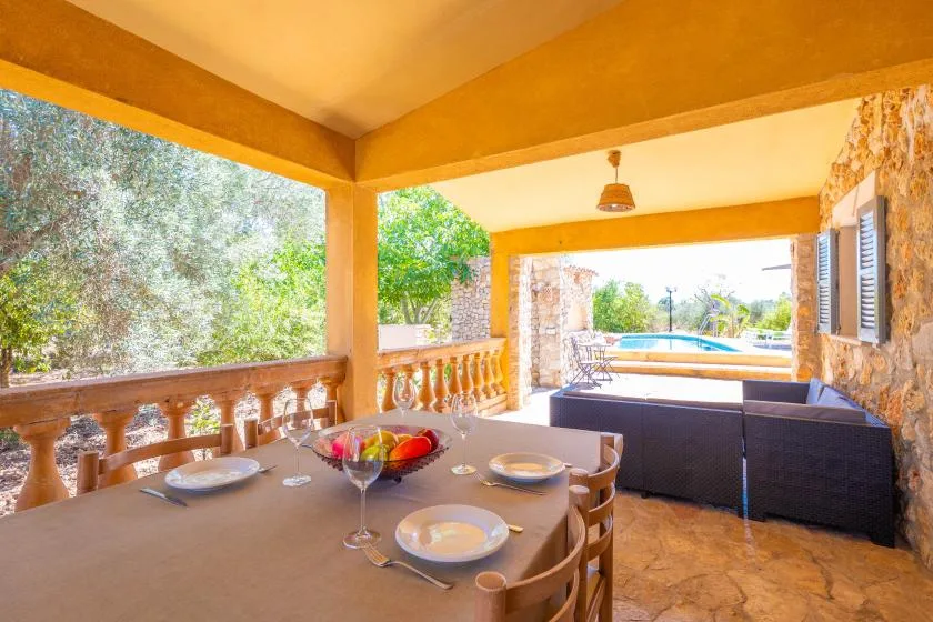 Un patio cubierto tiene una mesa de comedor y asientos con vista a una piscina.