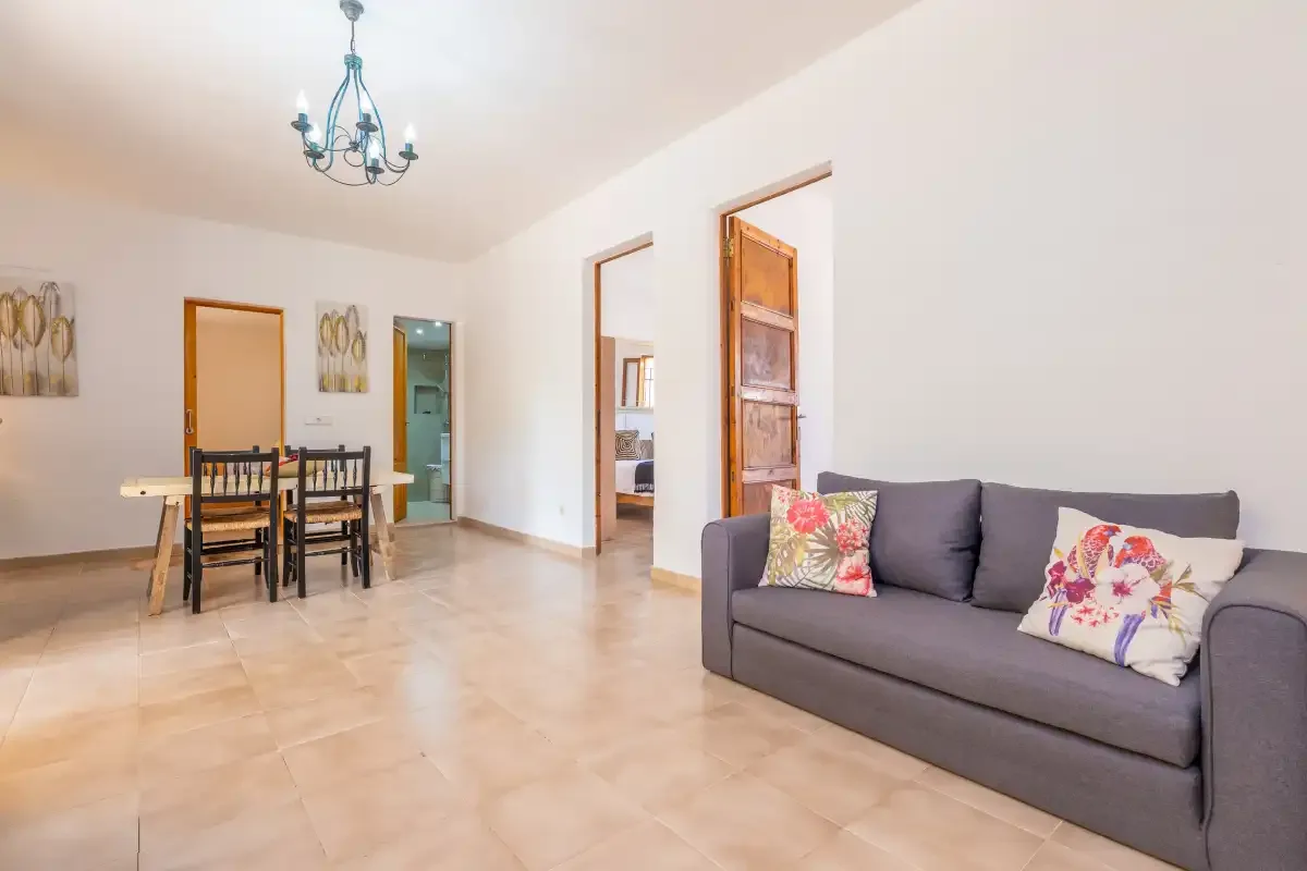 Una luminosa sala de estar y comedor con asientos, una mesa de comedor y una puerta abierta.
