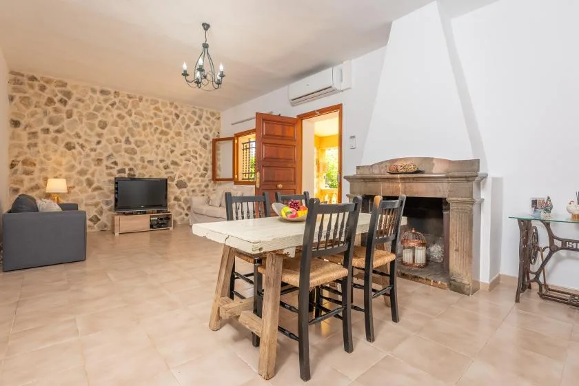 Un comedor con una mesa de madera está junto a una sala de estar y una chimenea de piedra.