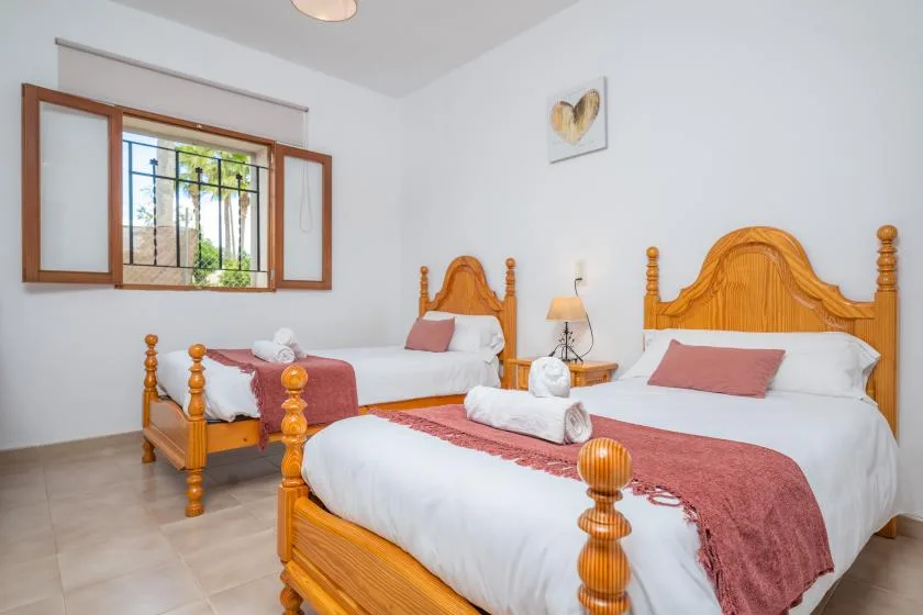 Un dormitorio con dos camas de madera, ropa de cama blanca y una ventana.