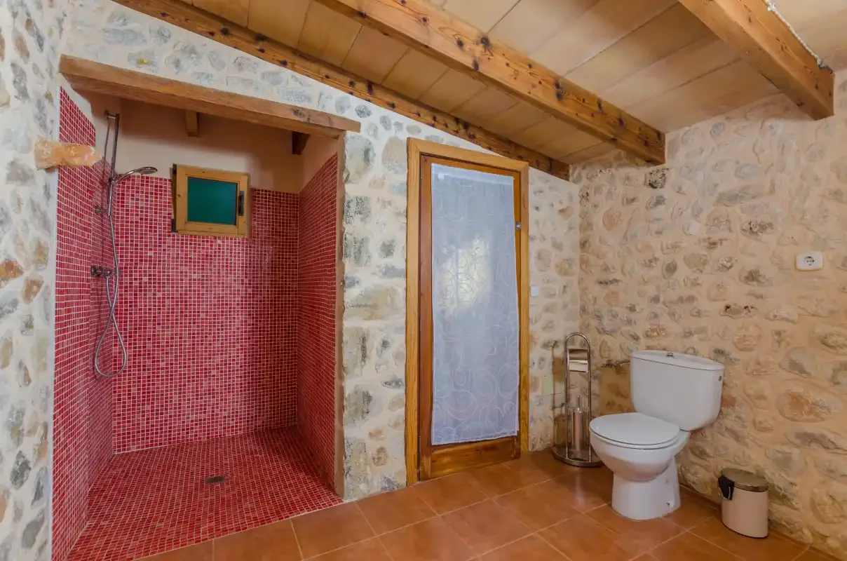 Un baño rústico con una ducha de azulejos rojos y un inodoro.