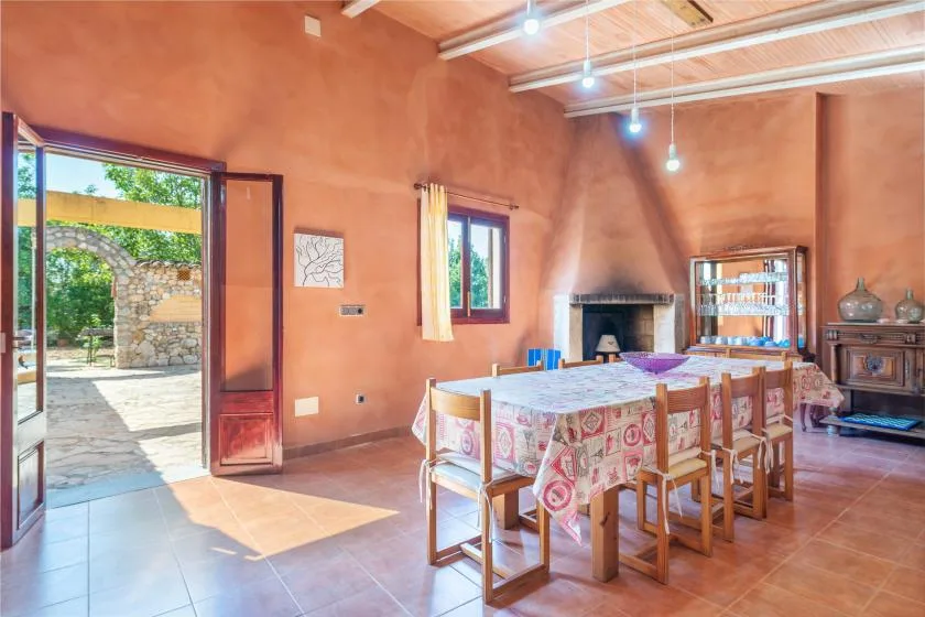 Un comedor con una mesa larga y sillas junto a una puerta abierta.