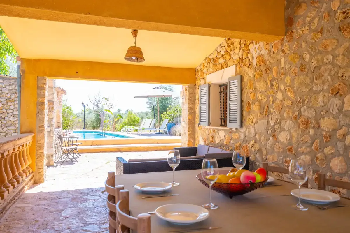 Una terraza cubierta de piedra tiene una mesa de comedor y asientos con vistas a una piscina.