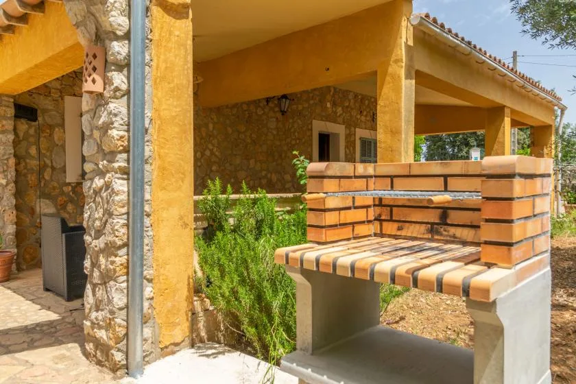 Patio exterior cubierto con una barbacoa de ladrillo y paredes de piedra.