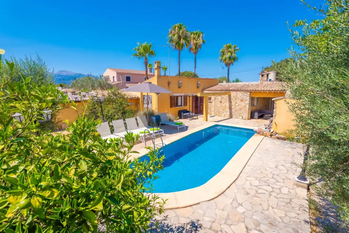 Una piscina está junto a un patio pavimentado con piedra y un edificio bajo.