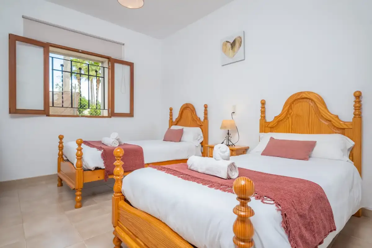 Un dormitorio con dos camas y una ventana con contraventanas de madera.