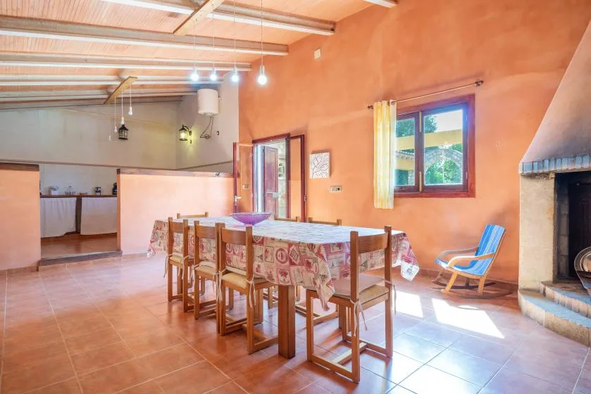 Comedor con una mesa larga y sillas junto a una ventana y una chimenea.