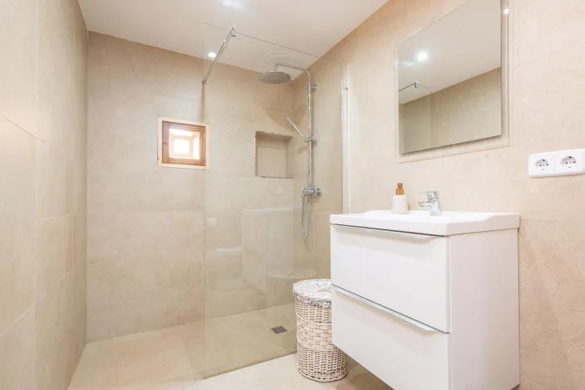 Un baño con azulejos, ducha de vidrio, lavabo y espejo de pared.