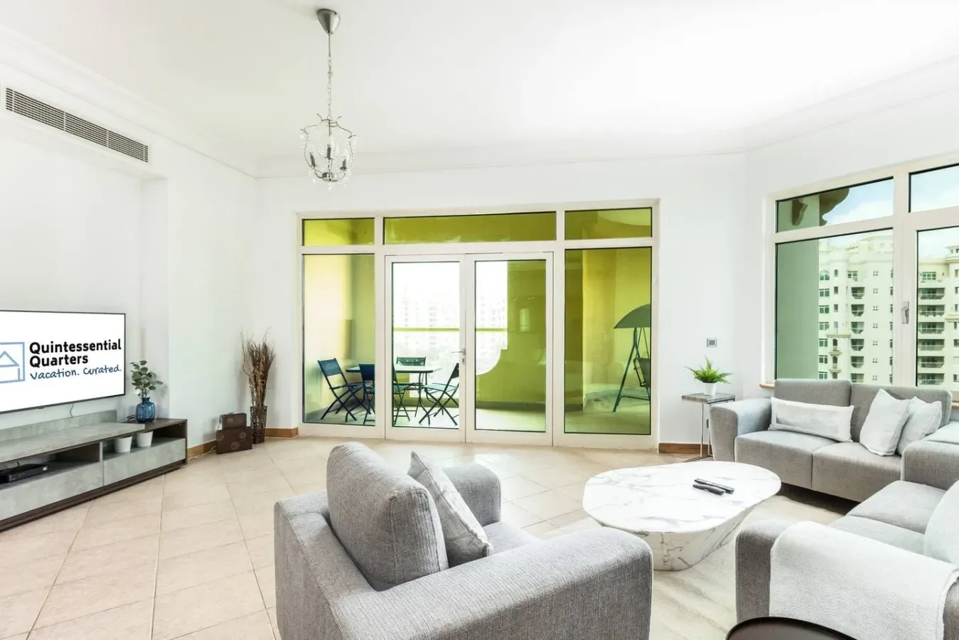 Una sala de estar luminosa con asientos, una mesa de centro y grandes ventanas.