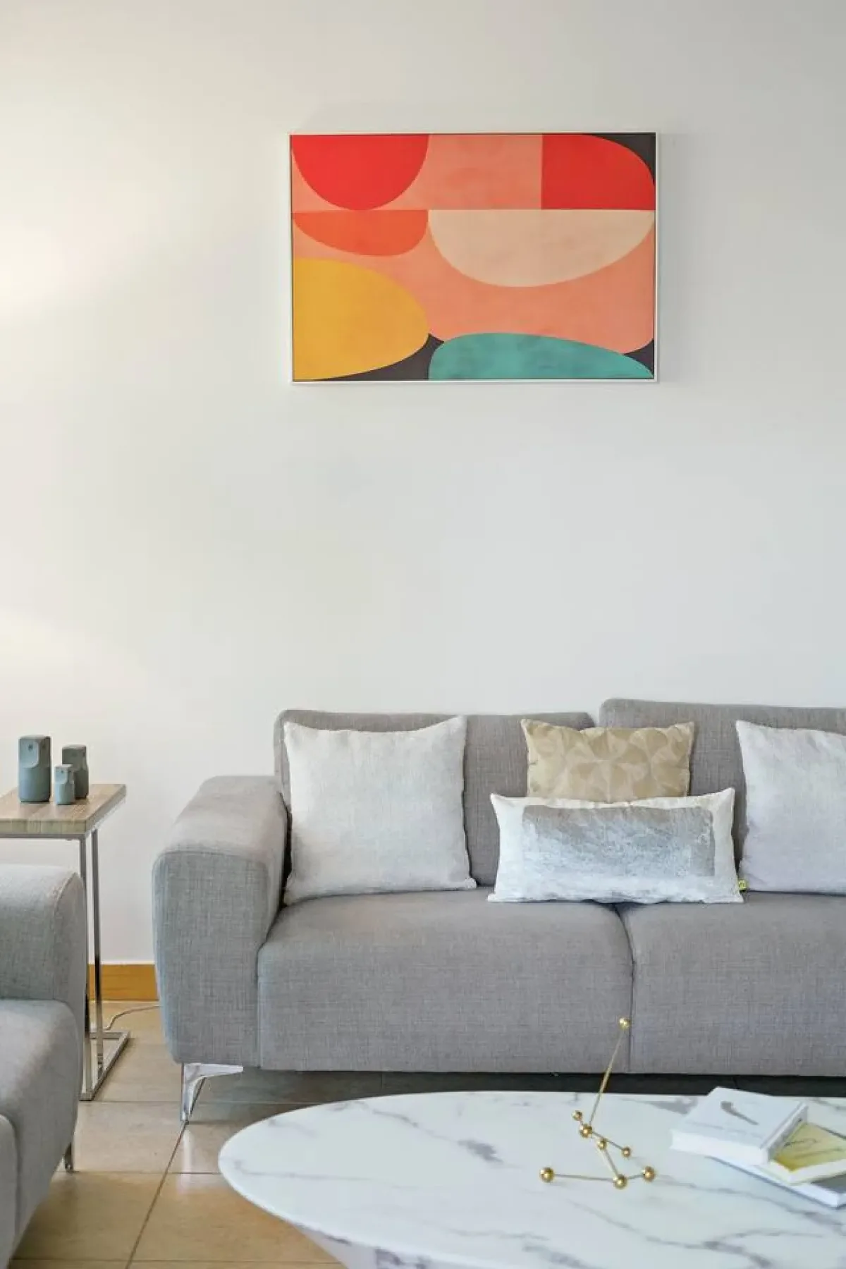 A living room with a gray sofa beneath colorful abstract wall art.